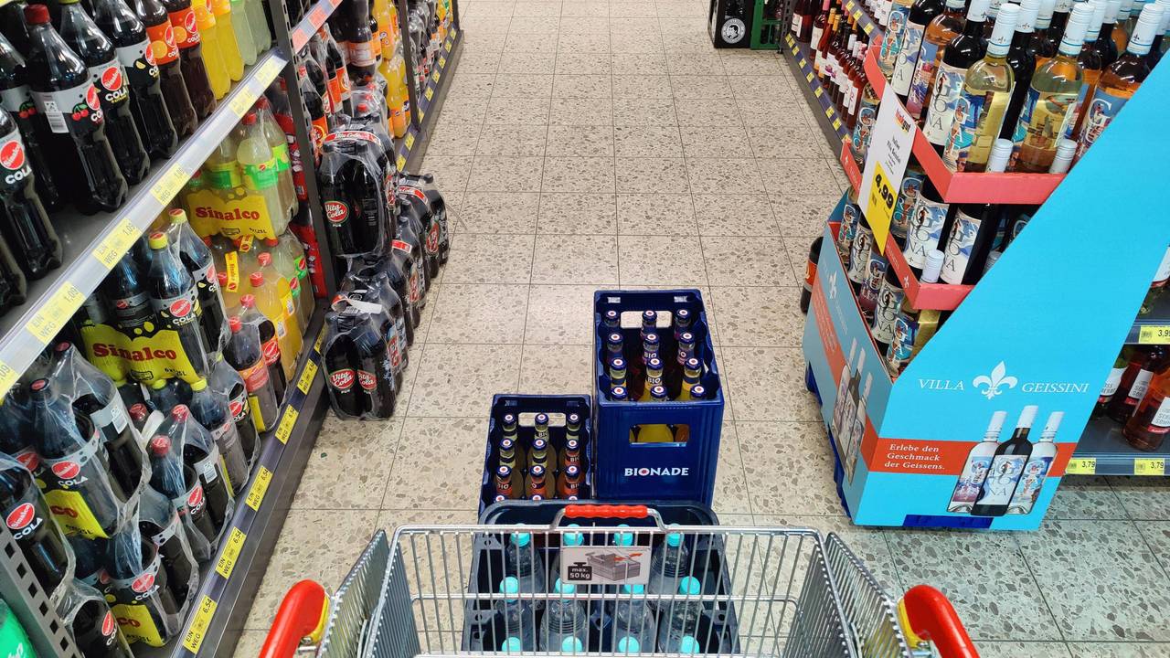 Einkaufswagen wird durch einen Gang im Getränkemarkt geschoben.