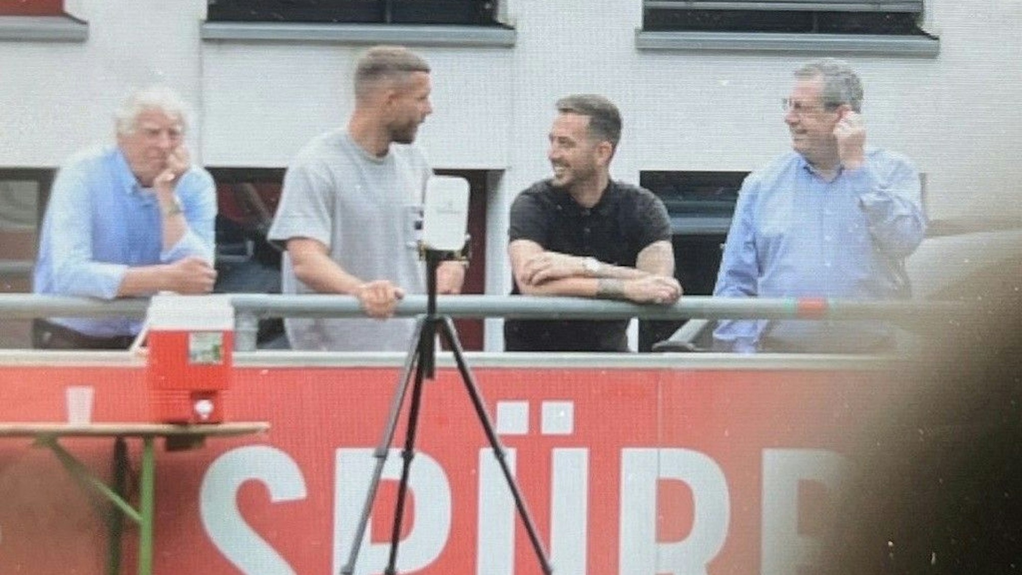 Lukas Podolski verfolgt das Training des 1. FC Köln am 16. Juli 2024 am Geißbockheim an der Seite von Erich Rutemöller, Kevin Brandenburg und Werner Wolf.