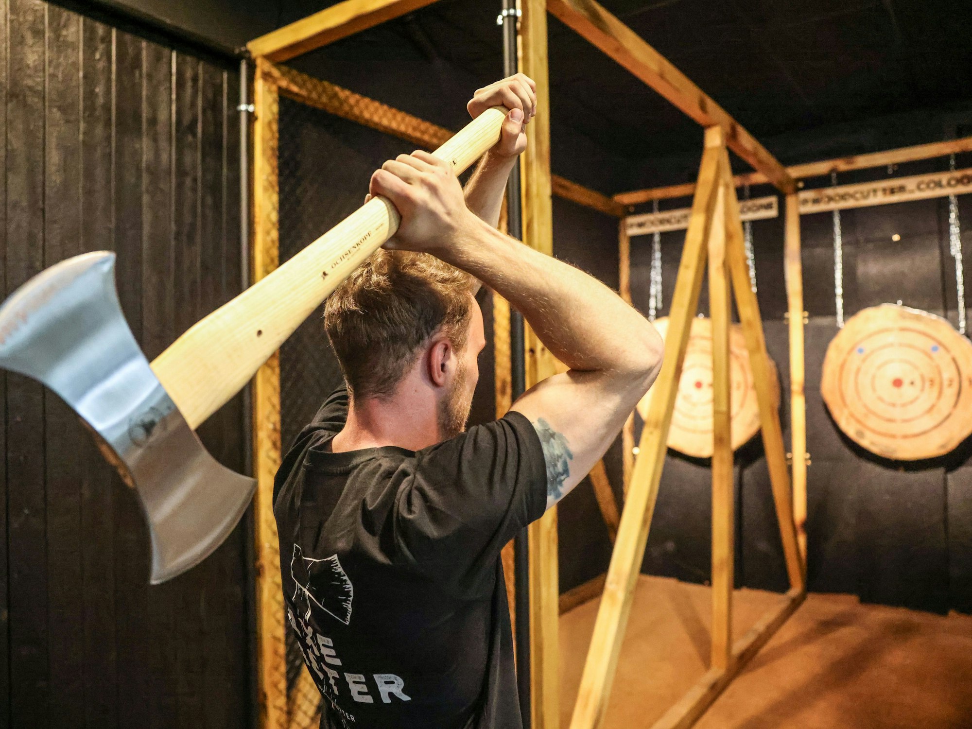 Aron Lack wirft in der Axtwurf-Bar eine Axt auf eine Holzscheibe.