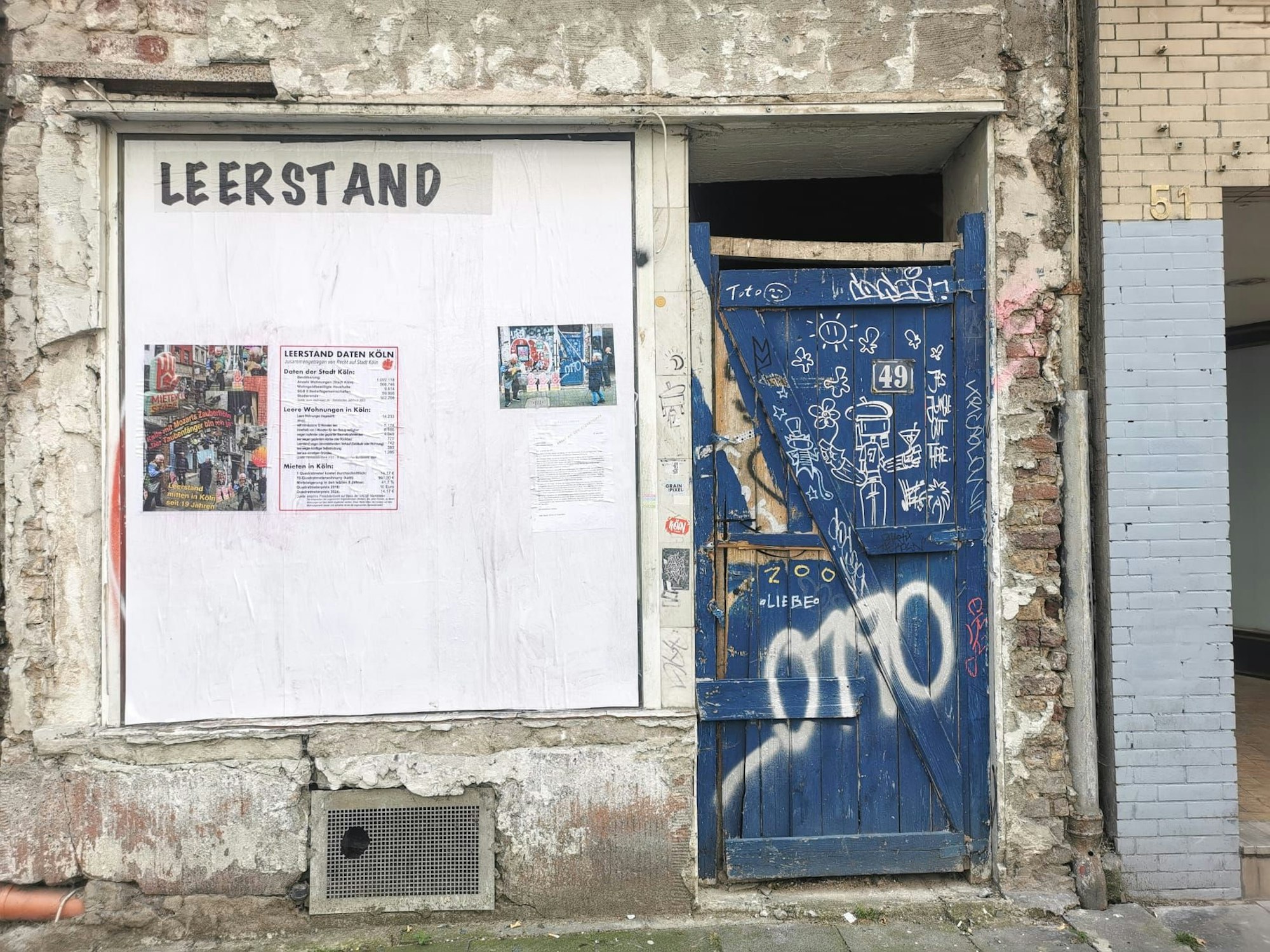 Blick auf einen Hauseingang mit einem Plakat an der Fassade.