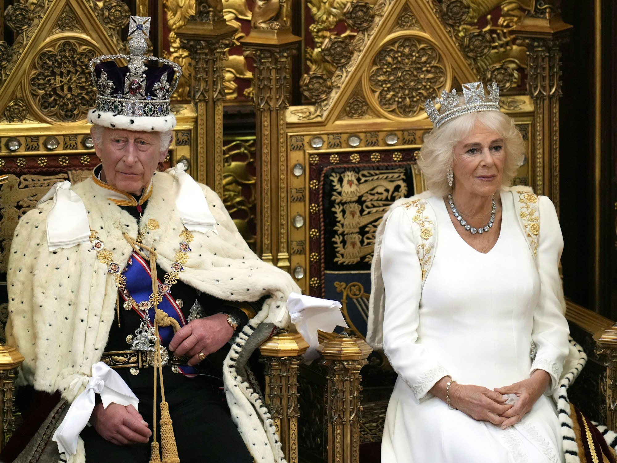 König Charles III. blickt auf, während er darauf wartet, die Rede des Königs zu verlesen, als Königin Camilla bei der Eröffnung des Parlaments im House of Lords neben ihm Platz nimmt.