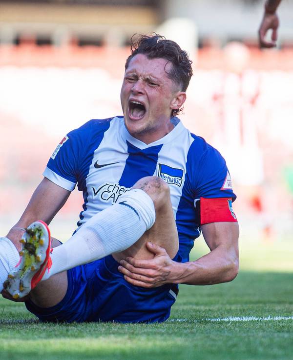 Hertha BSC Kapitän Fabian Reese hält sich mit schmerzverzerrtem Gesicht den Knöchel.