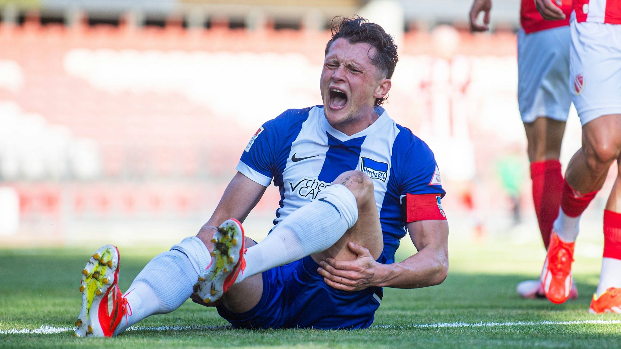 Hertha BSC Kapitän Fabian Reese hält sich mit schmerzverzerrtem Gesicht den Knöchel.