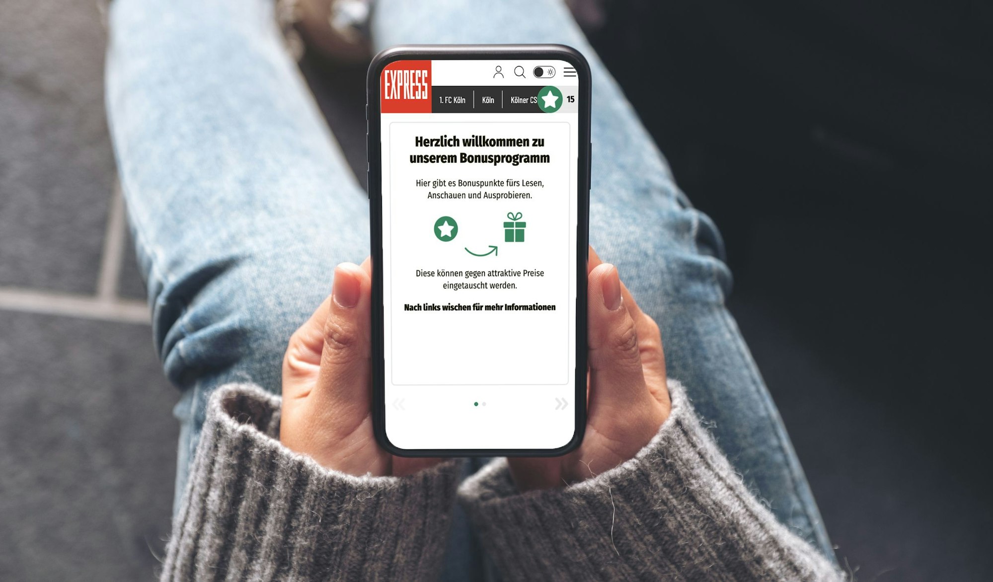 Eine Person hält ein Handy mit dem Bonusprogramm von EXPRESS.de