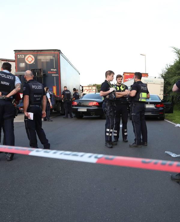 Einsatzkräfte der Polizei stehen an einem Tatort an einem Rastplatz an der Autobahn.
