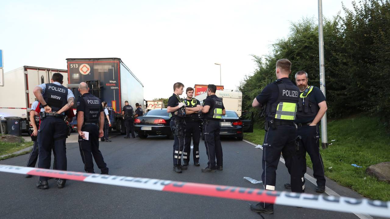 Einsatzkräfte der Polizei stehen an einem Tatort an einem Rastplatz an der Autobahn.