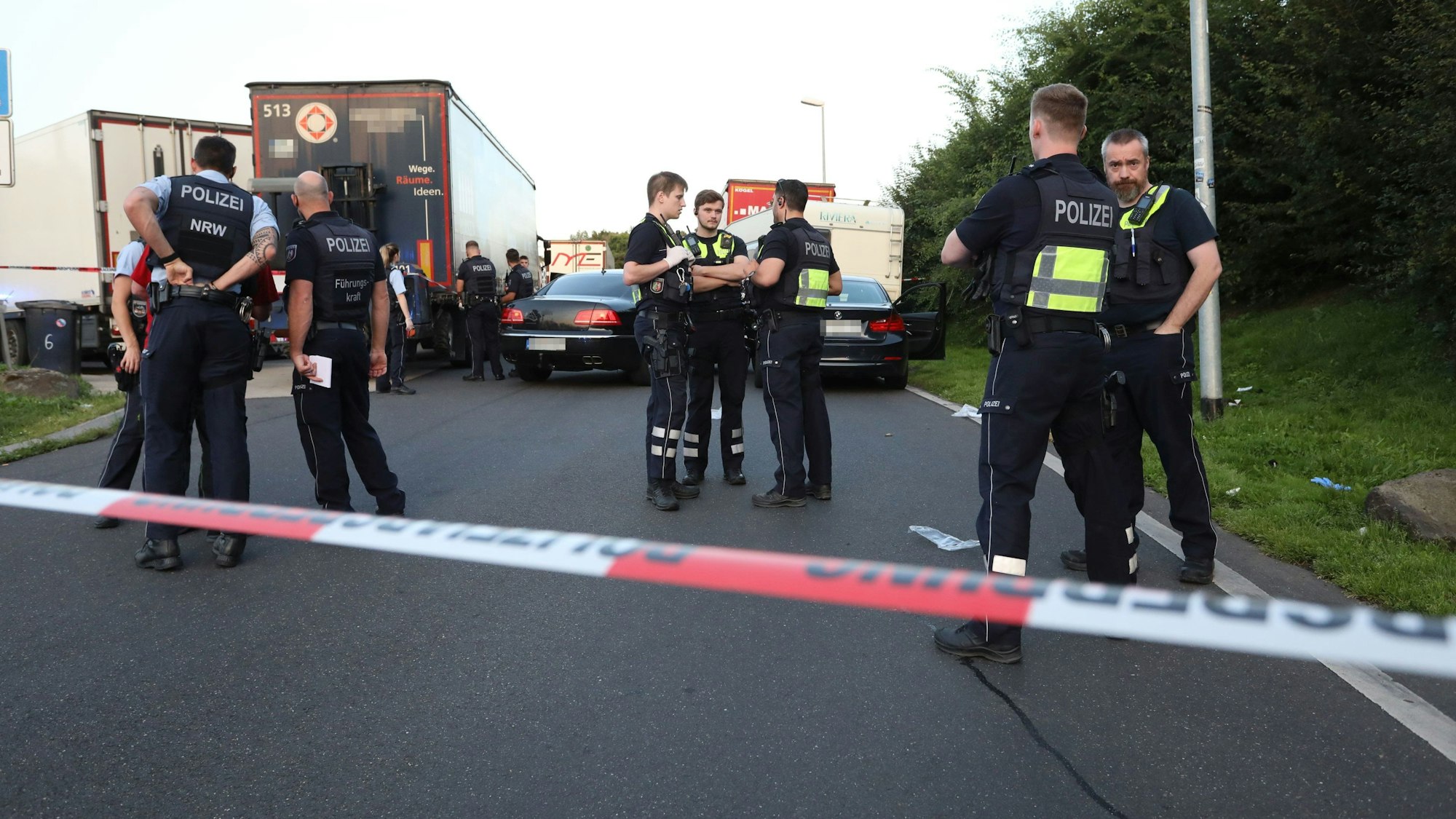 Einsatzkräfte der Polizei stehen an einem Tatort an einem Rastplatz an der Autobahn.