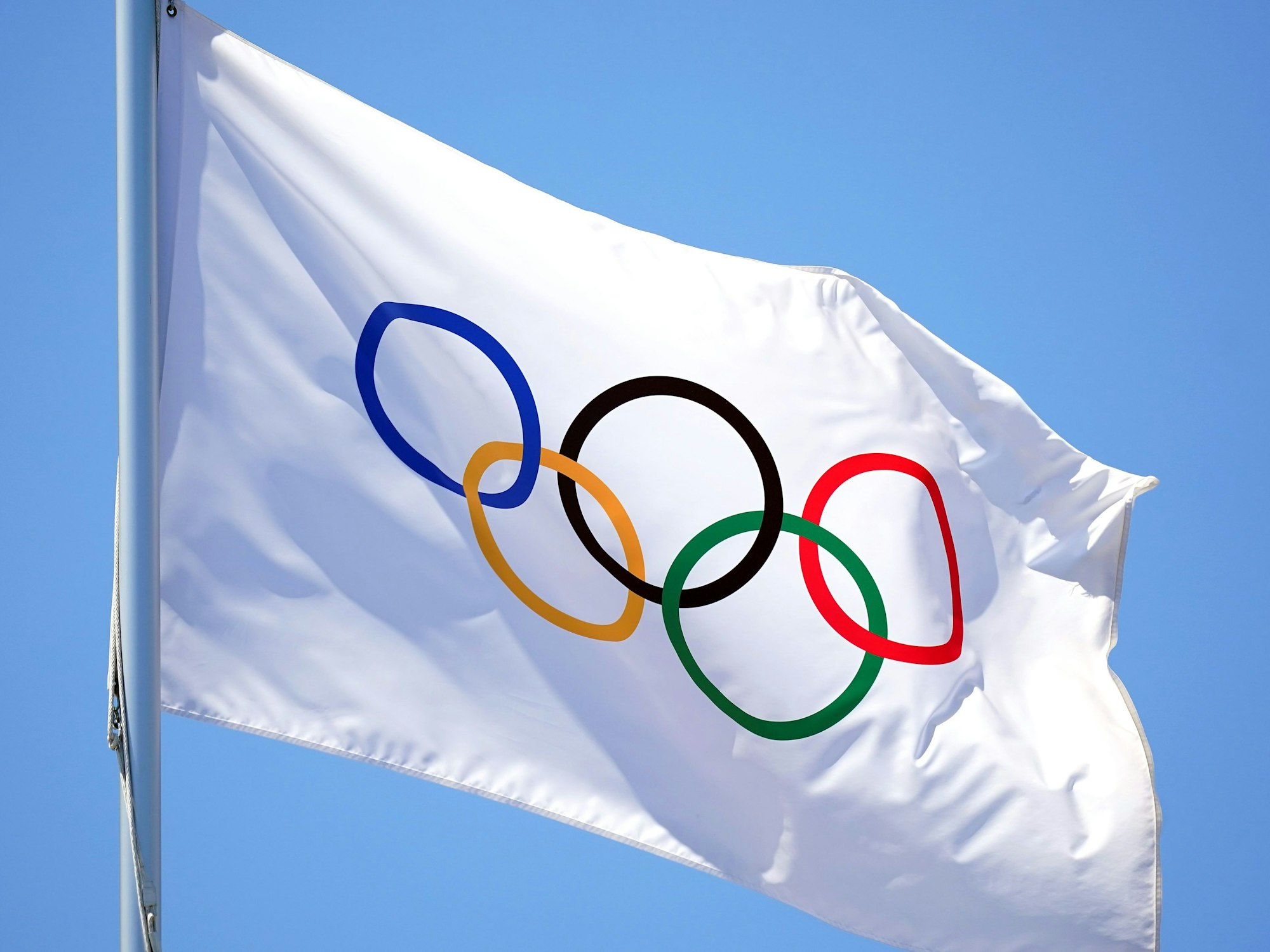 Eine Flagge mit den olympischen Ringen weht im Wind.