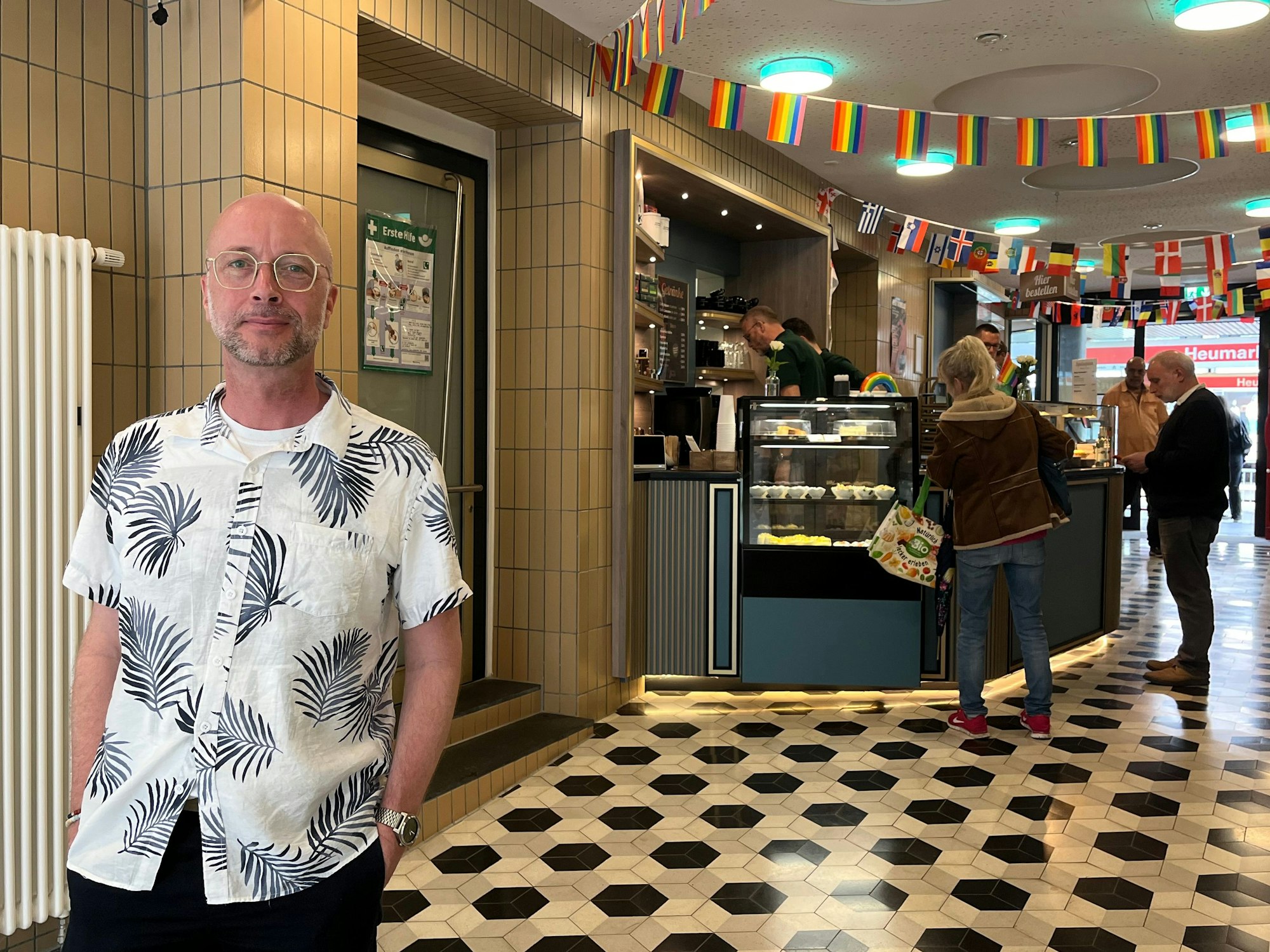 Oliver Schubert, Geschäftsführer der Kölner Aidshilfe, steht vor dem Café Bach. Die Gastronomie hat seinen Namen in Erinnerung an den im Jahr 2012 verstorbenen Kölner Schauspieler Dirk Bach erhalten. Sie fungiert auch als Kontakt- und Begegnungsstätte. Menschen mit und ohne HIV kommen hier ins Gespräch.
