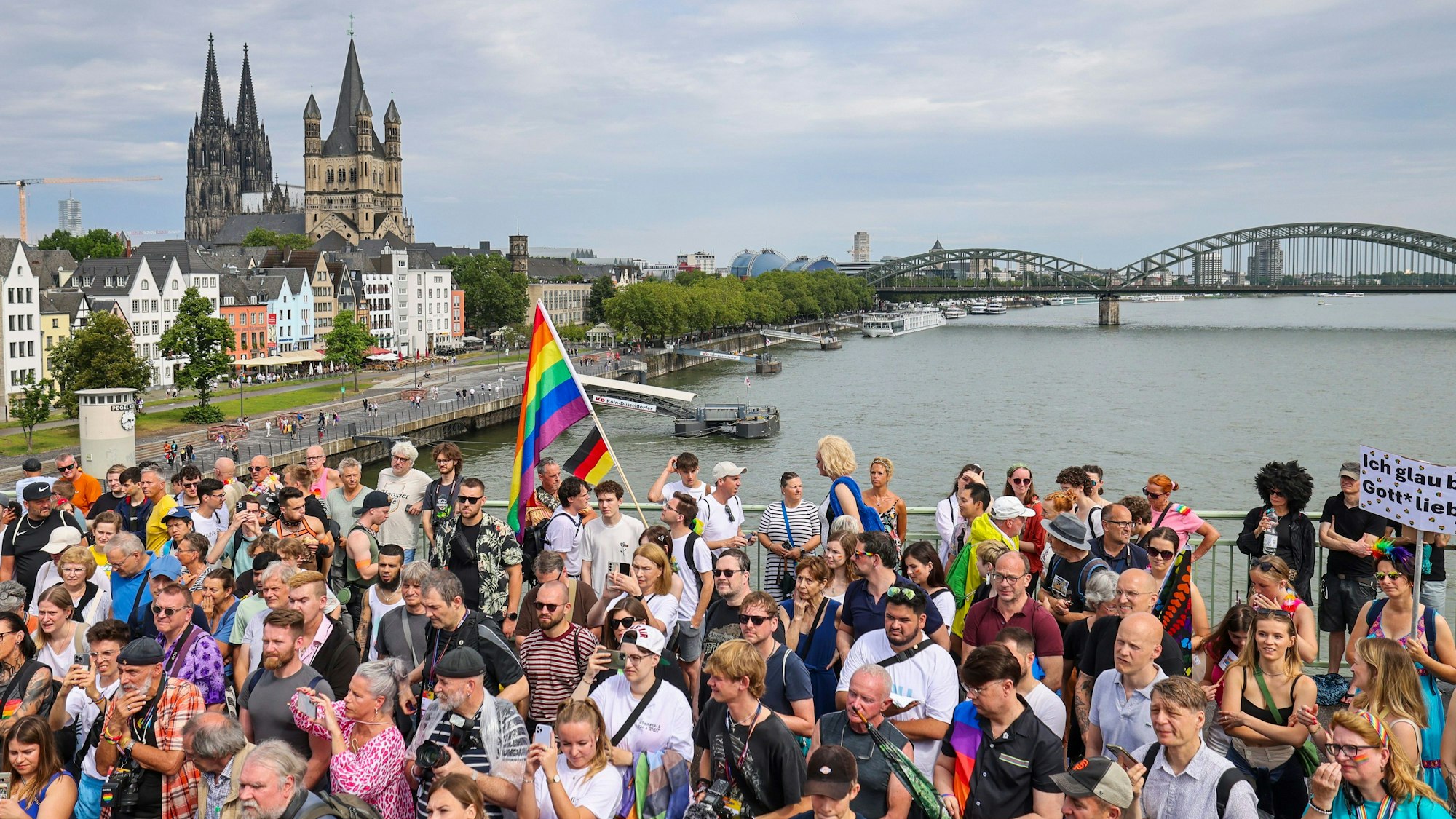 Viele Menschen stehen auf einer Brücke in Köln und feiern bei der CSD-Parade die queeren Rechte.