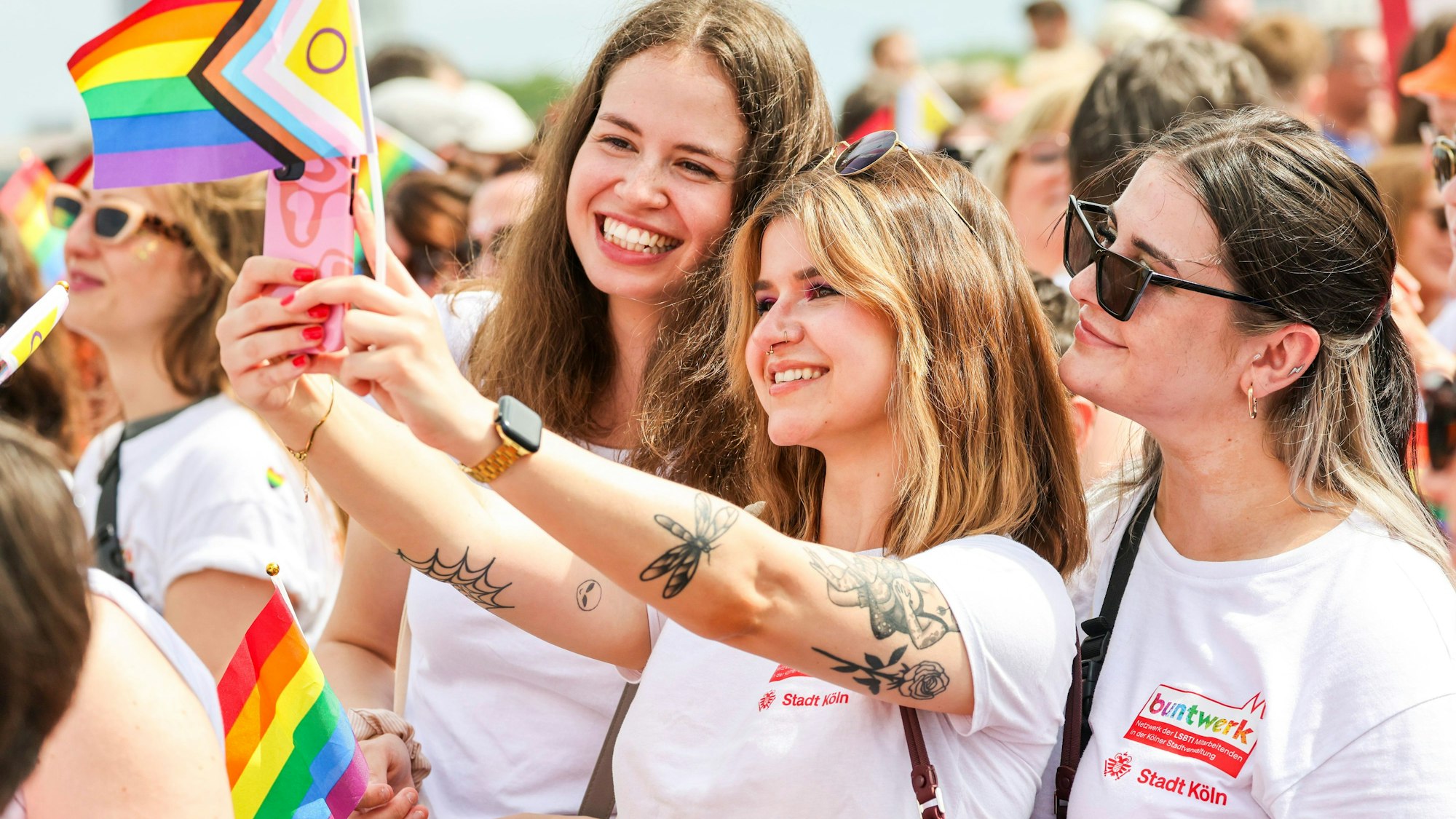 Drei Teilnehmerinnen machen Selfies beim CSD in Köln.