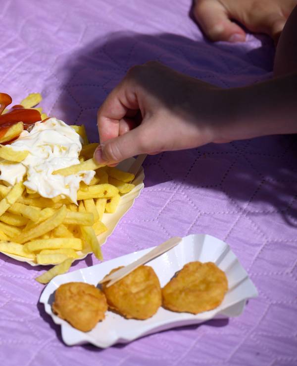 Drei Freibad-Gäste teilen sich eine Pommes.