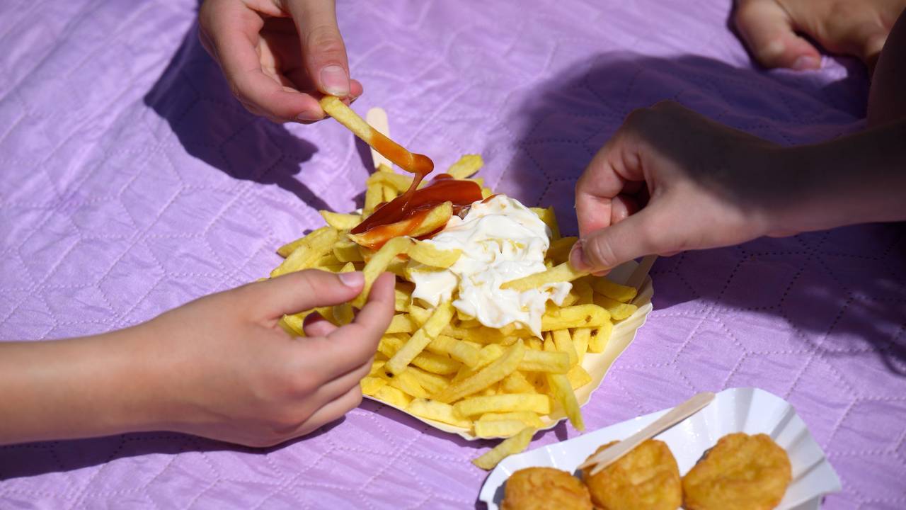Drei Freibad-Gäste teilen sich eine Pommes.