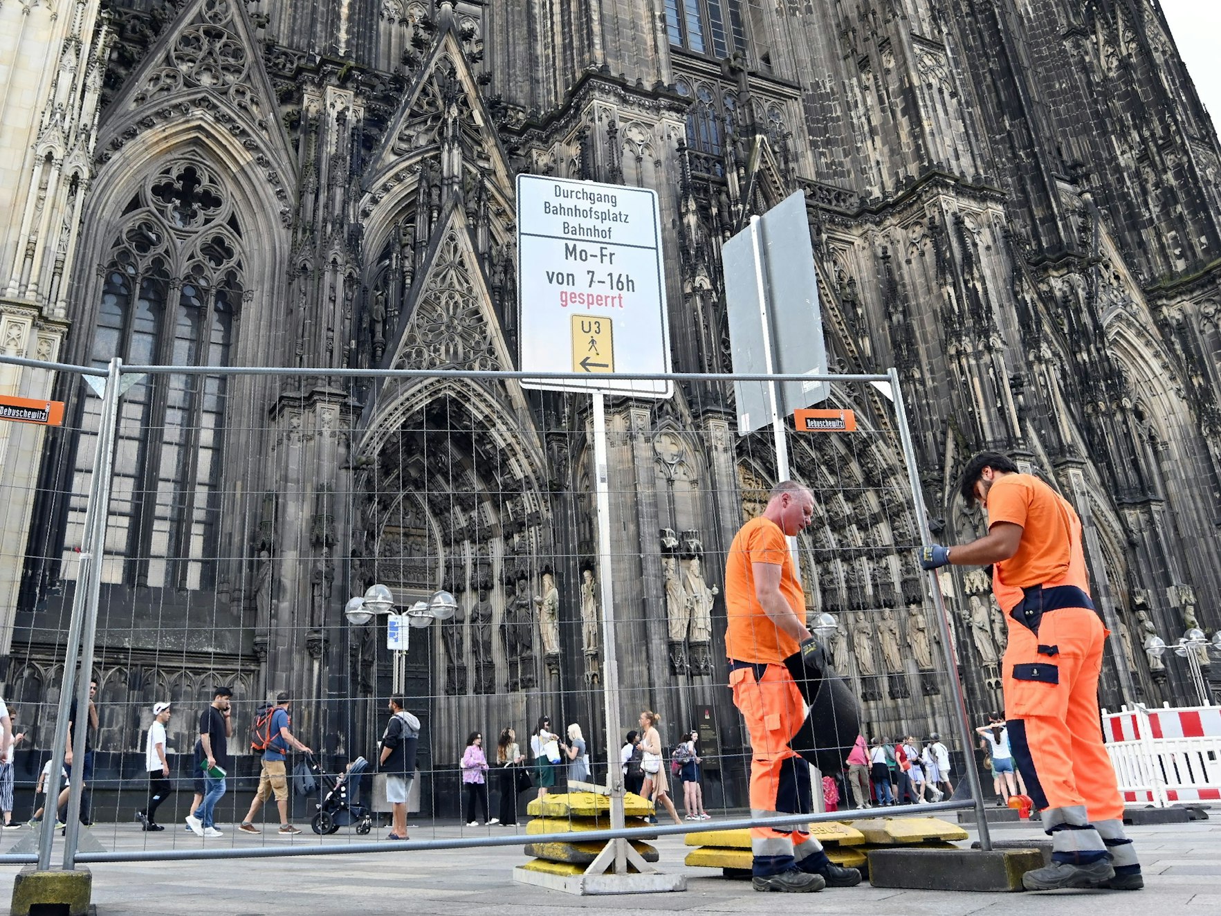 Zwei Arbeiter stellen einen Zaun auf.