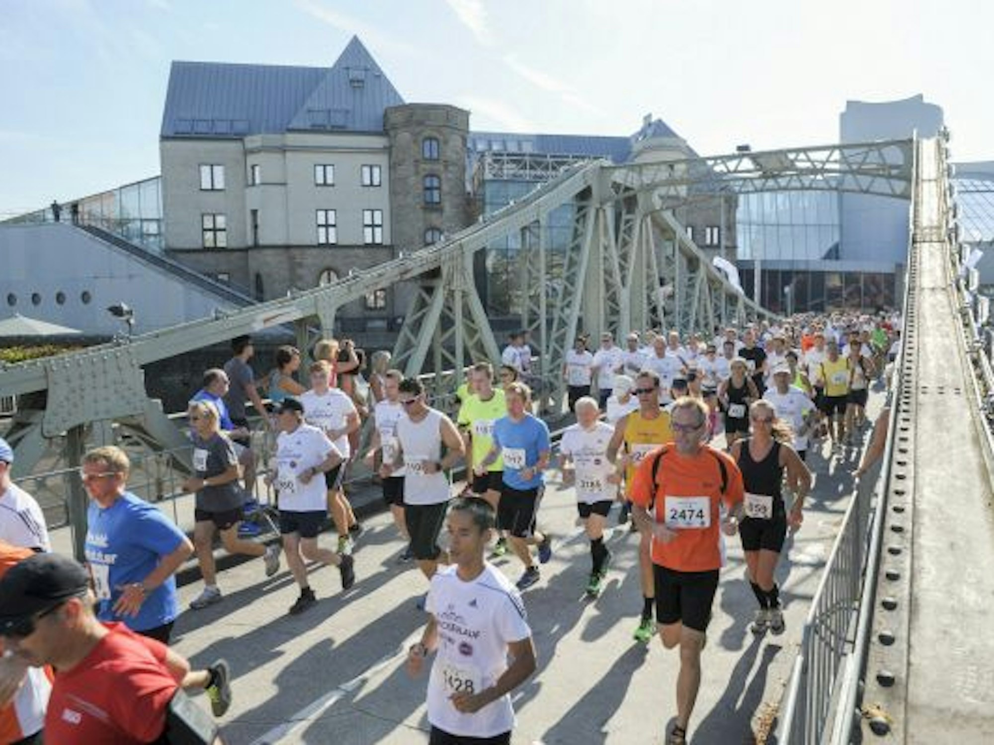 Zahlreiche Menschen laufen über eine Brücke.
