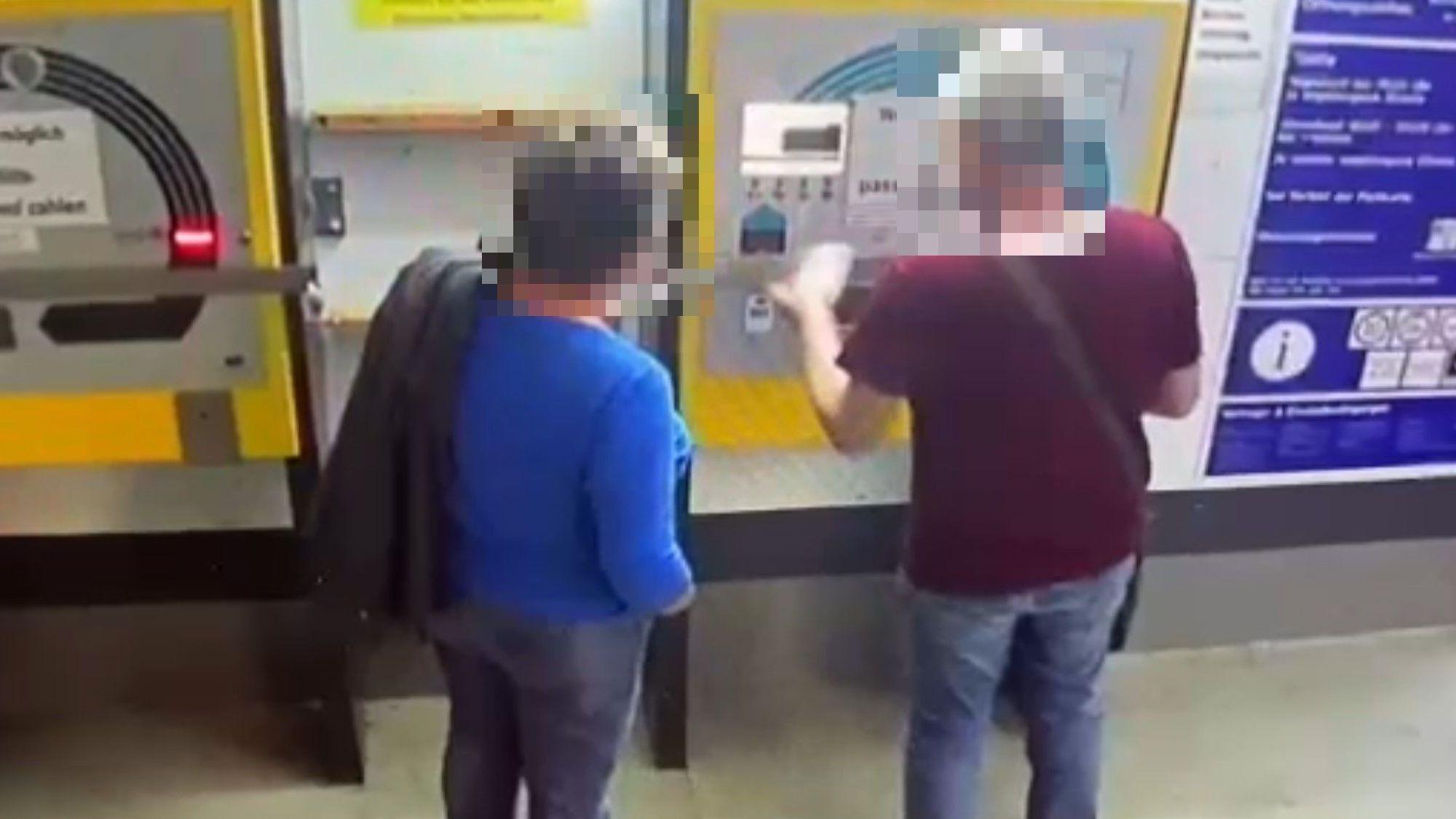 Ein Mann und eine Frau stehen vor einem Parkscheinautomaten in einem Parkhaus in Köln.