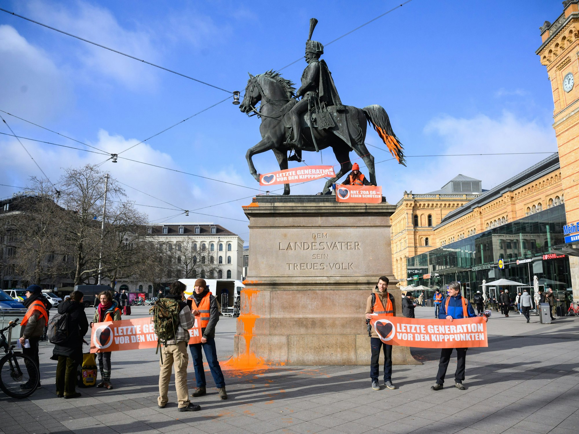 Aktivistin der Letzten Generation demonstrieren vor und auf dem Ernst-August-Denkmal vor dem Hauptbahnhof.
