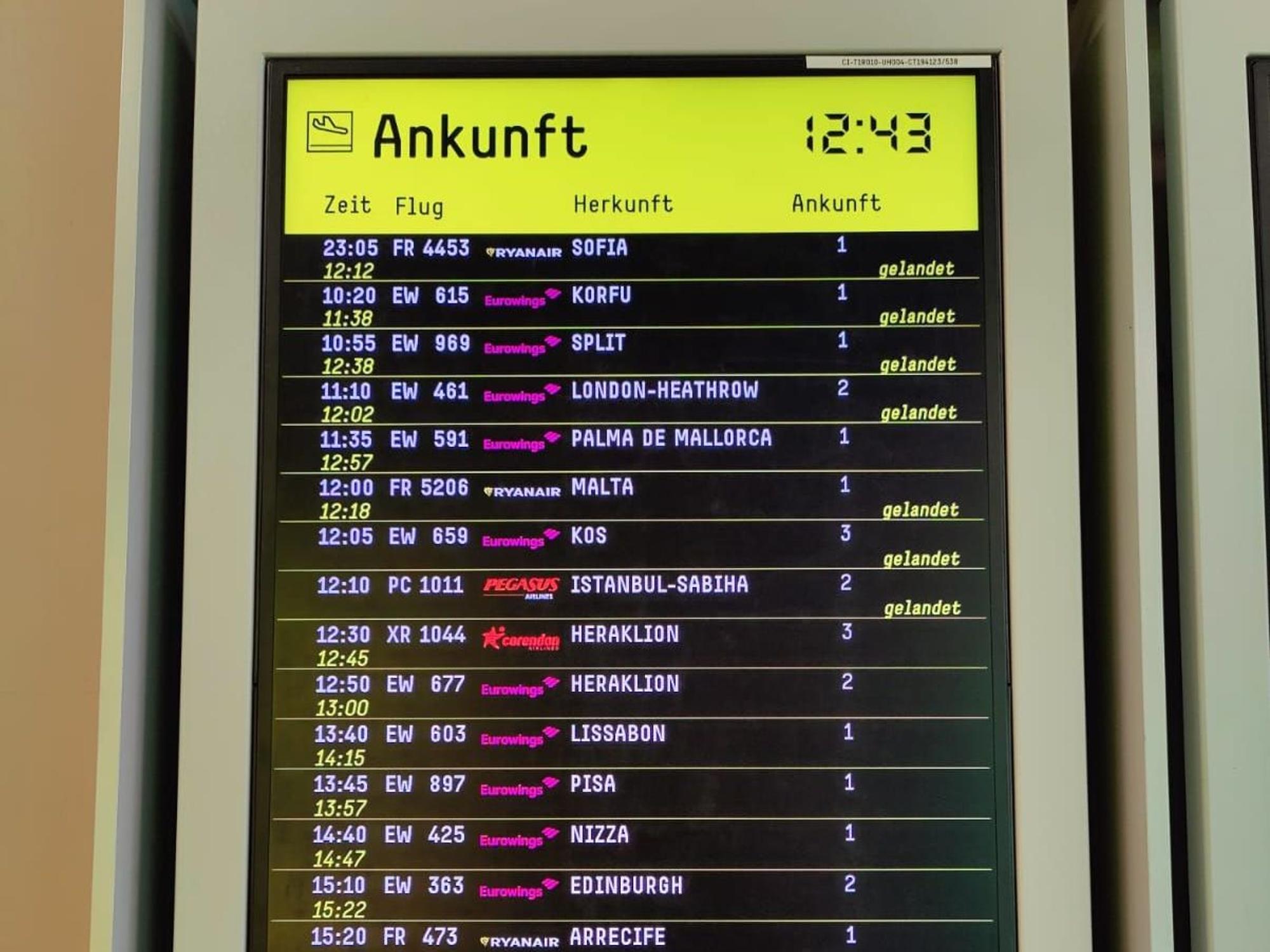 Eine digitale Tafel zeigt die Ankunftszeiten von Flugzeugen.