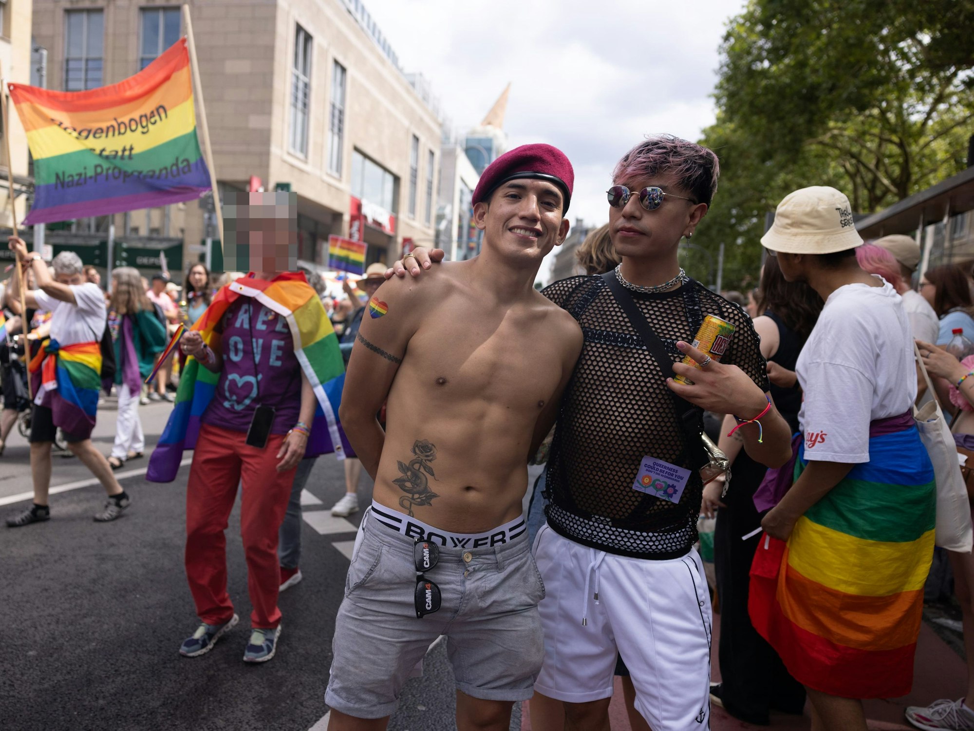Zwei Männer stehen bei einer CSD-Parade auf er Straße.