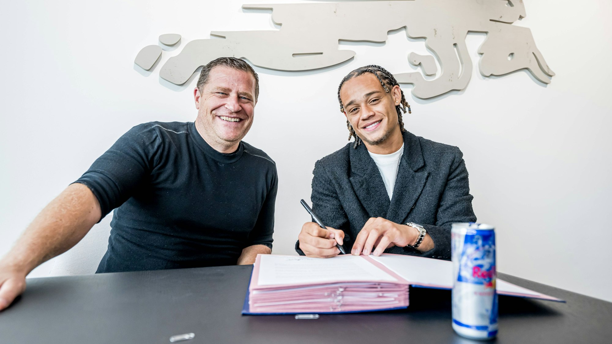 Max Eberl lacht und Xavi Simons unterschreibt seinen Vertrag in Leipzig.