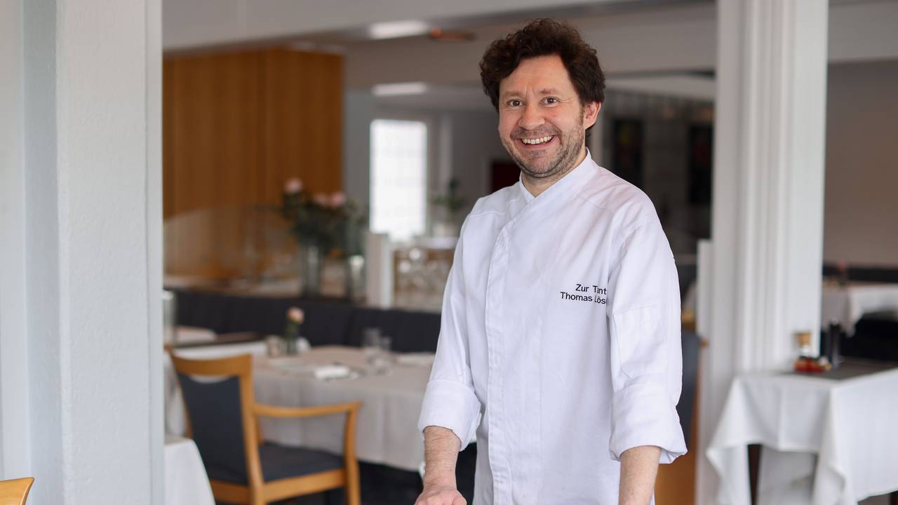 Koch Thomas Lösche steht an einem Stuhl in seinem Restaurant