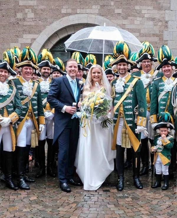 Ein Brautpaar steht mitten einer Karnevalsgruppe.