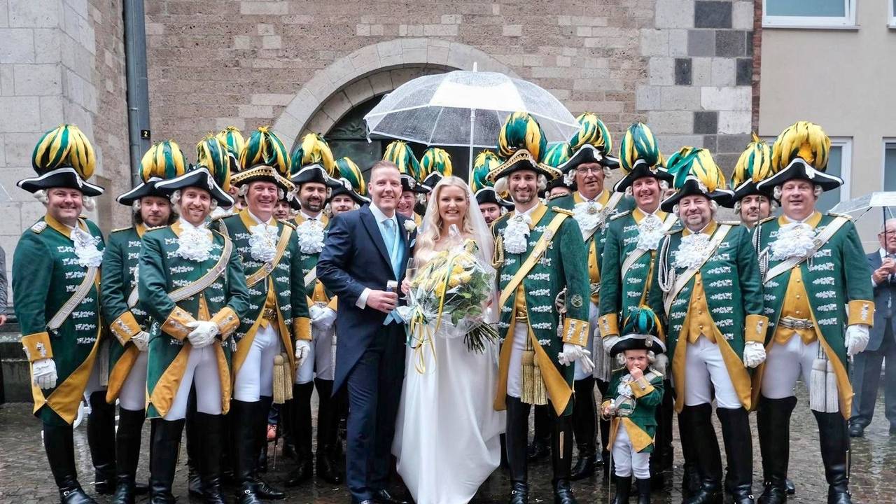 Ein Brautpaar steht mitten einer Karnevalsgruppe.