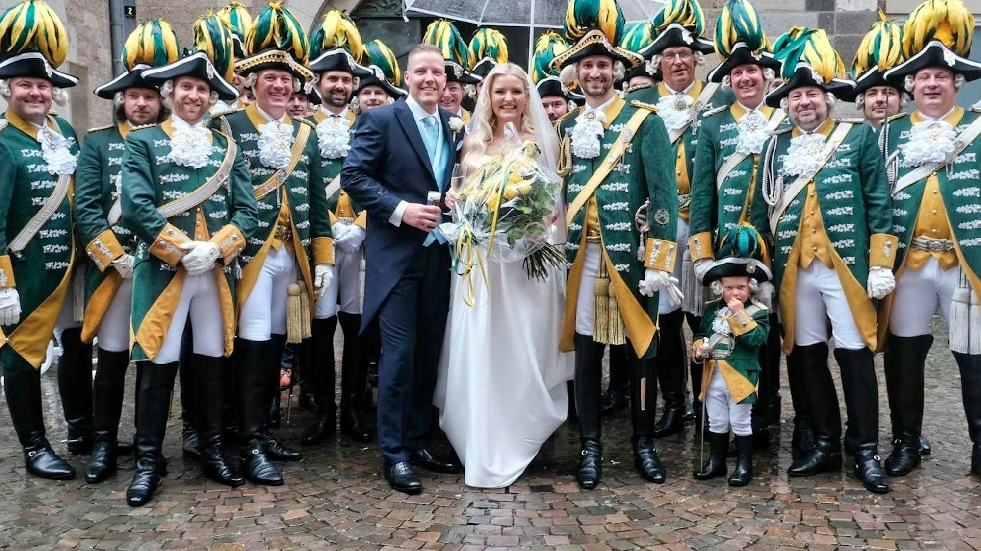 Ein Brautpaar steht mitten einer Karnevalsgruppe.