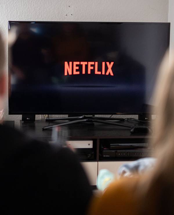 Ein Paar sitzt vor dem Fernseher, auf dem das Netflix-Logo zu sehen ist.