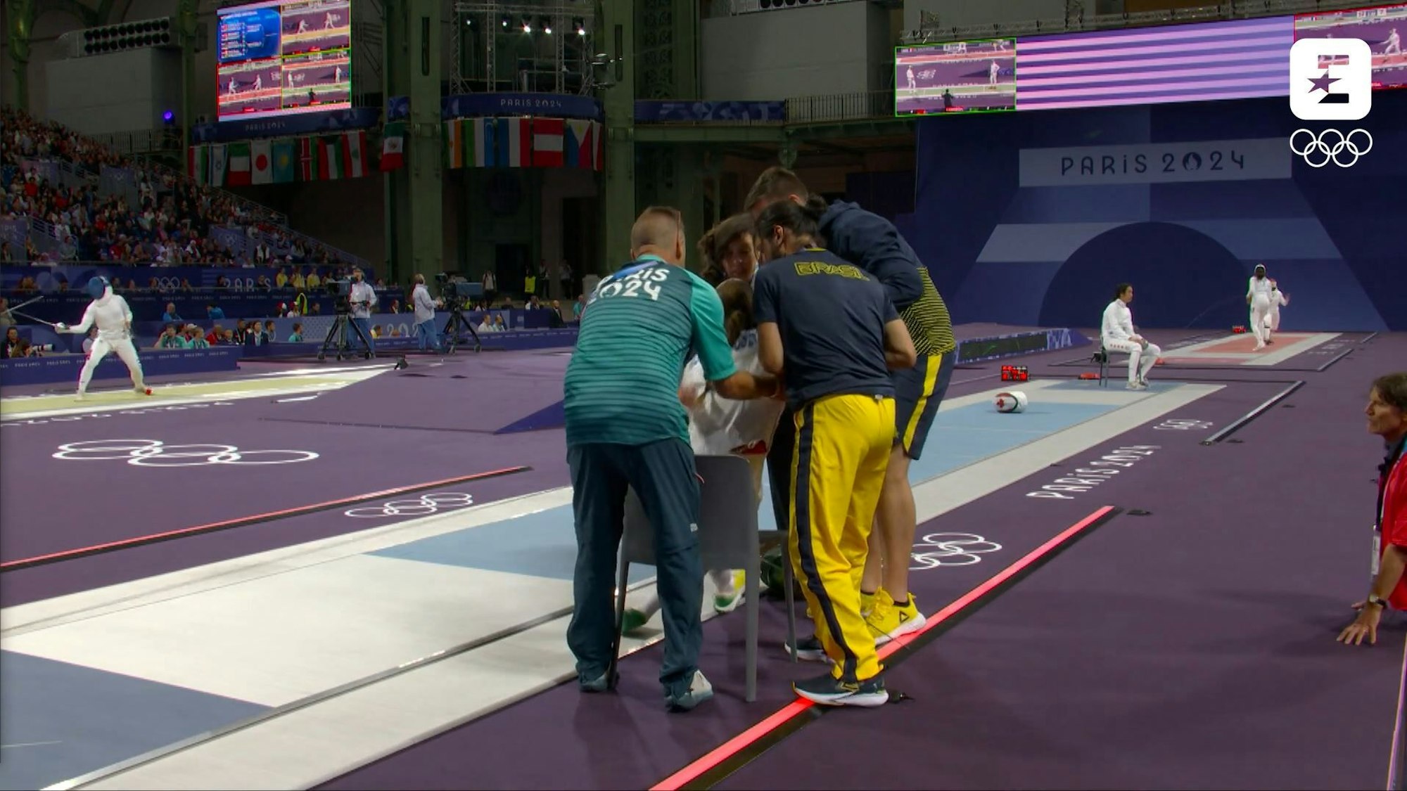 Nathalie Moellhausen mit einem Zusammenbruch bei ihrem Olympia-Gefecht. Sie wird von ihrem Team auf einen Stuhl gehievt.