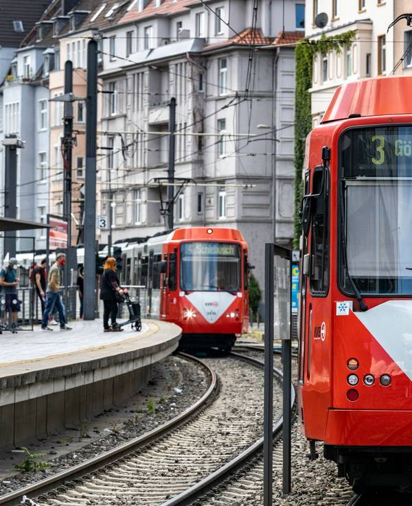 Zwei KVB-Bahnen fahren an einer Haltestelle vorbei.