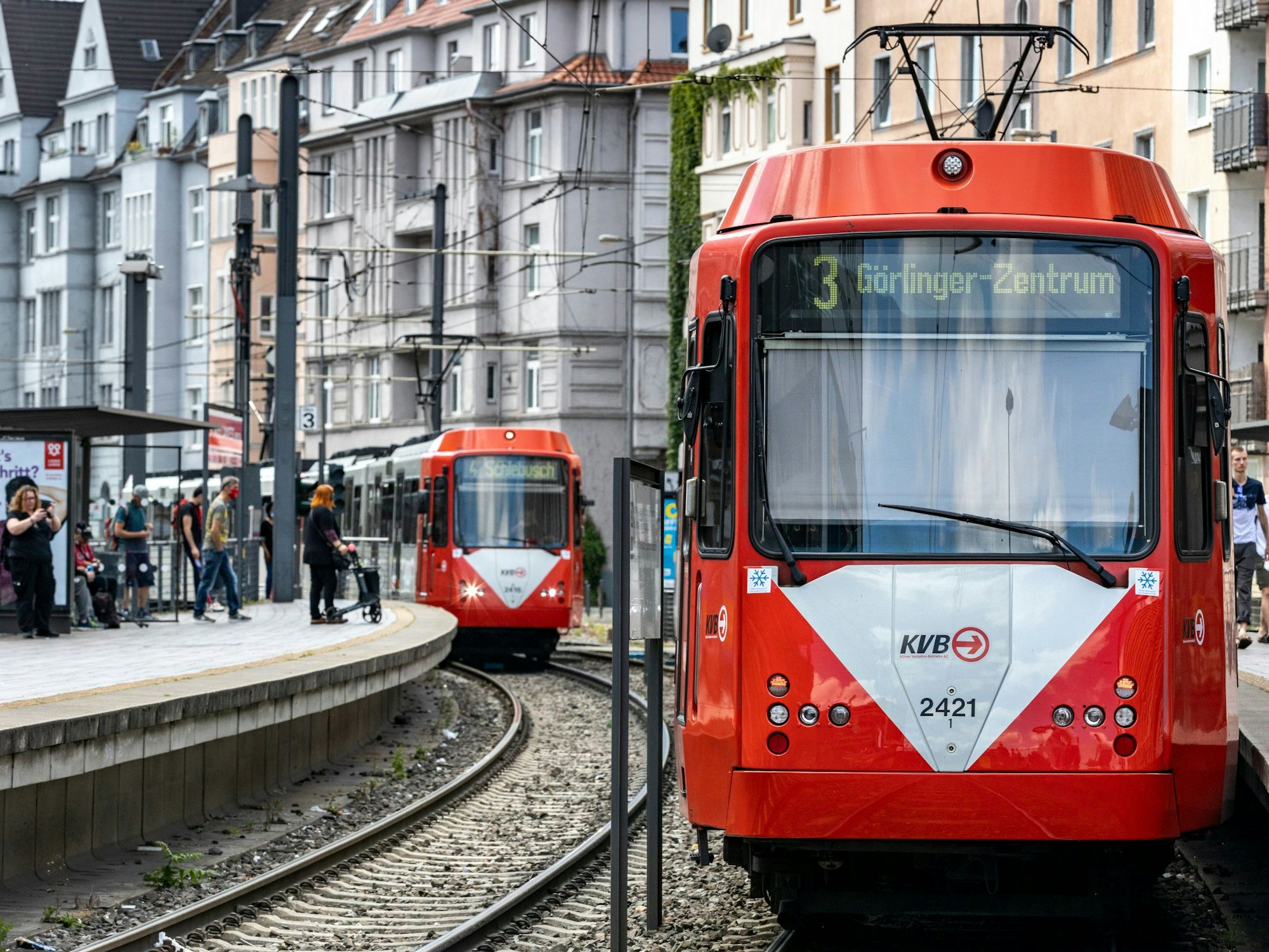 Zwei KVB-Bahnen fahren an einer Haltestelle vorbei.