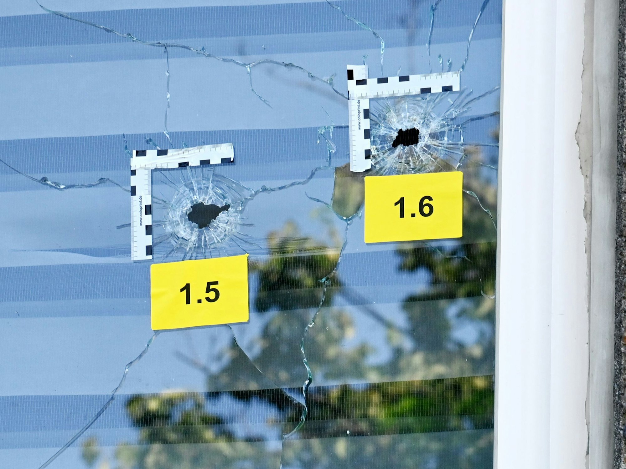 In einer Fensterscheibe sind zwei Einschusslöcher, die Polizei hat beide markiert.