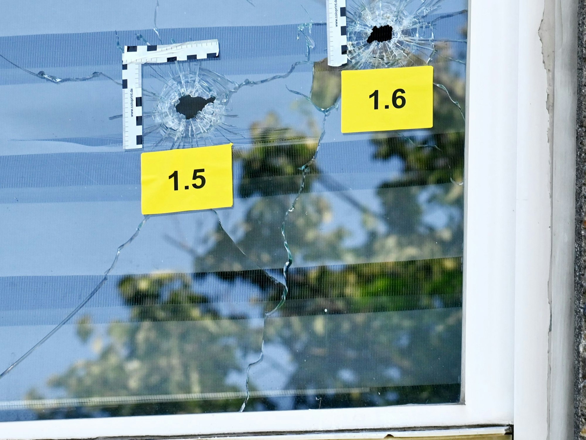 Die Polizei hat zwei Einschüsse in einer Fensterscheibe markiert.