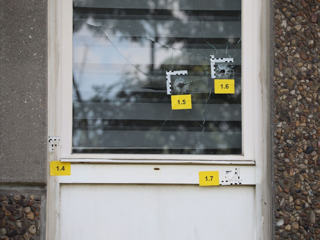Einschusslöcher sind an einem Fenster im Erdgeschoss eines Gebäudes zu sehen.