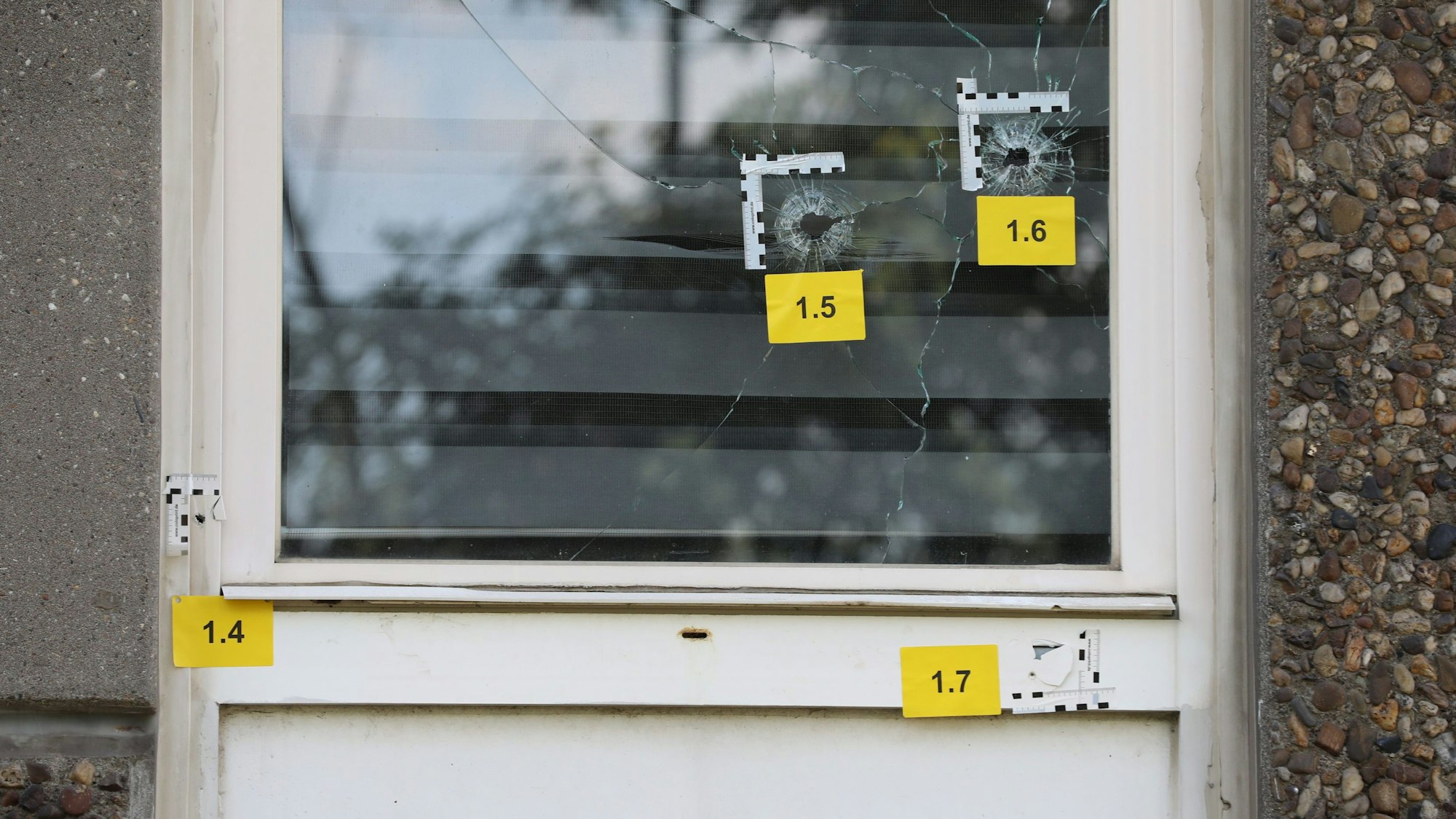 Einschusslöcher sind an einem Fenster im Erdgeschoss eines Gebäudes zu sehen.