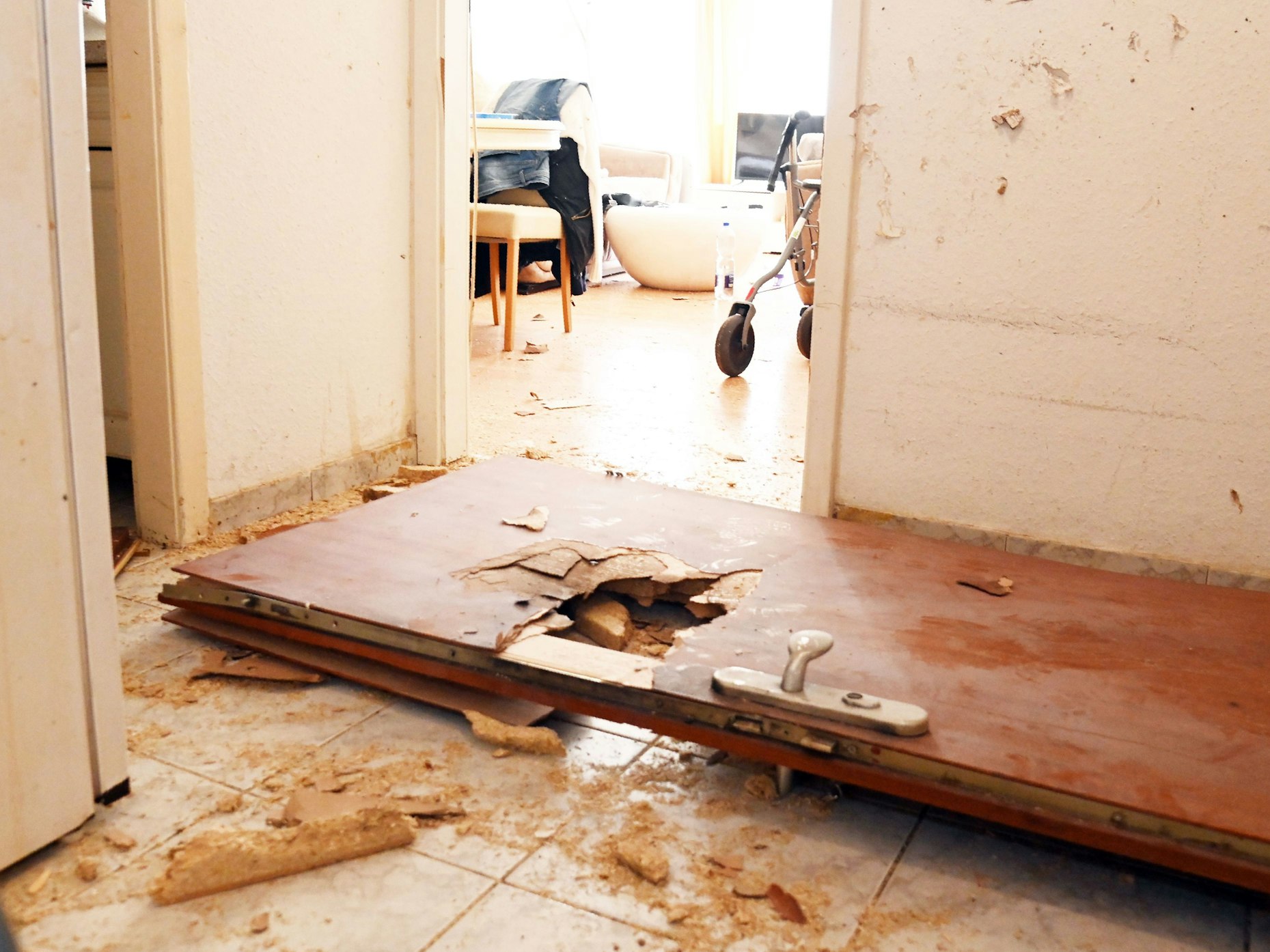Eine Wohnungstür liegt schwer beschädigt auf dem Boden.