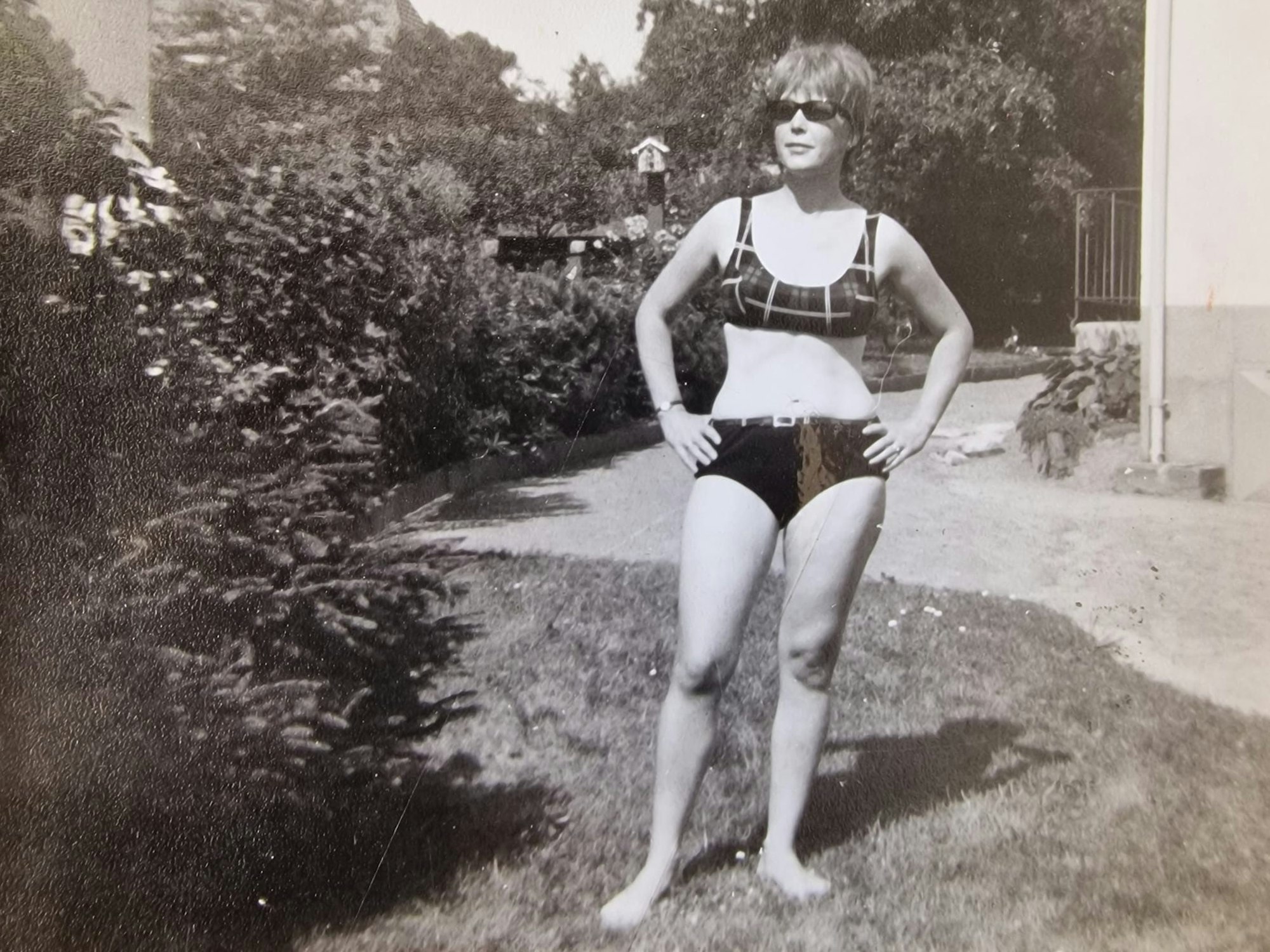 Eine Frau posiert im Bikini auf einem Rasenstück.