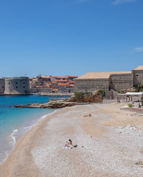 Vier Personen sonnen sich an der Adria an einem Strand in Kroatien.
