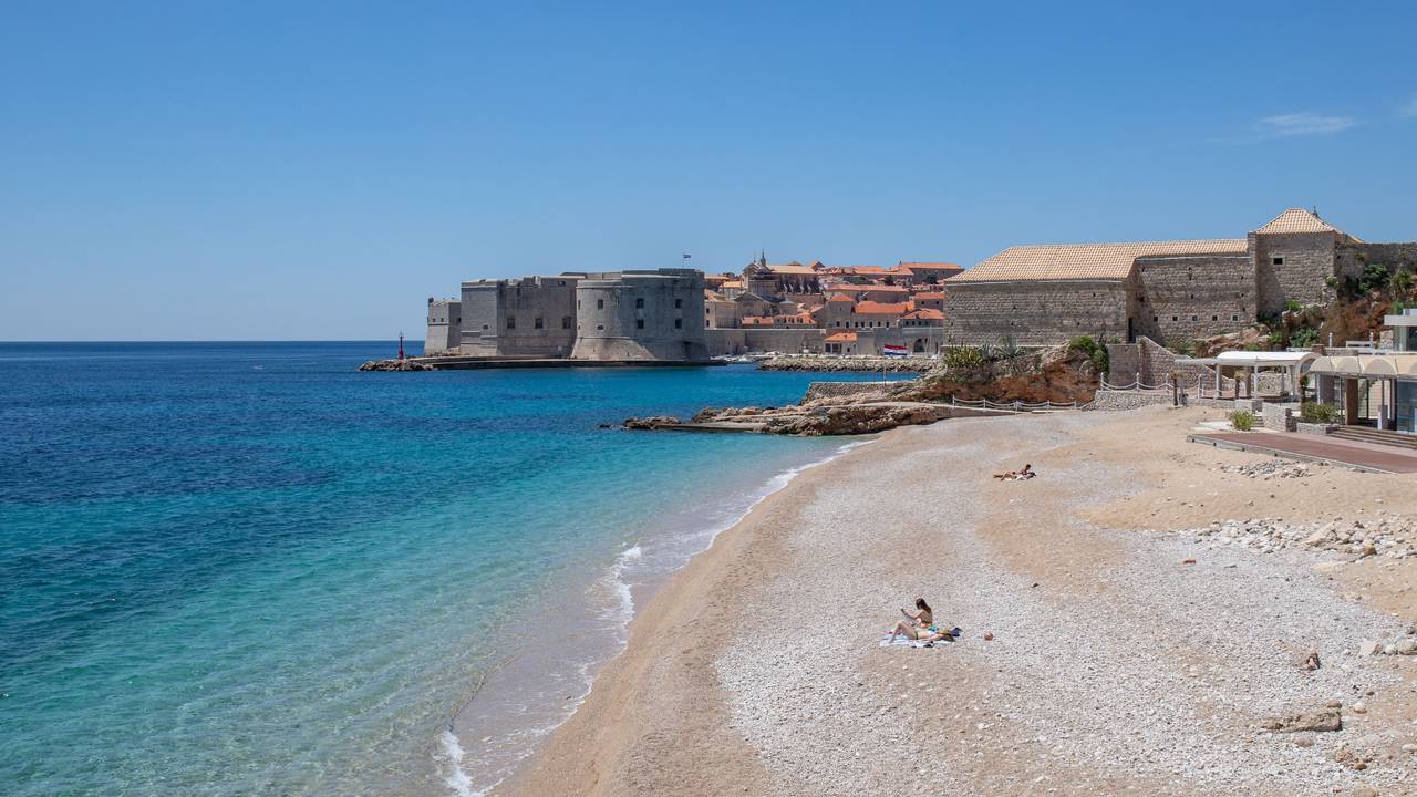Vier Personen sonnen sich an der Adria an einem Strand in Kroatien.