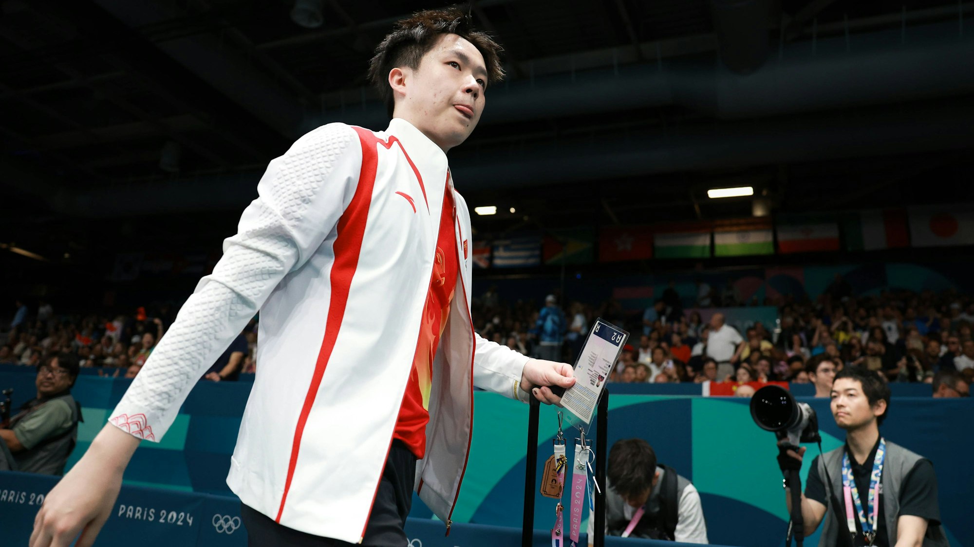 Der chinesische Tischtennis-Star Wang Chuqin kommt vor einem Spiel bei Olympia in die Halle.