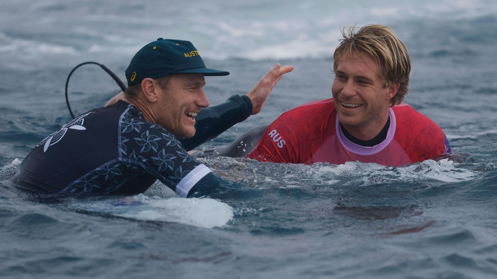 Olympia-Surfer Ethan Ewing (r.) beim Wettkampf am Dienstag (30. Juli 2024) im Gespräch mit seinem Trainer.