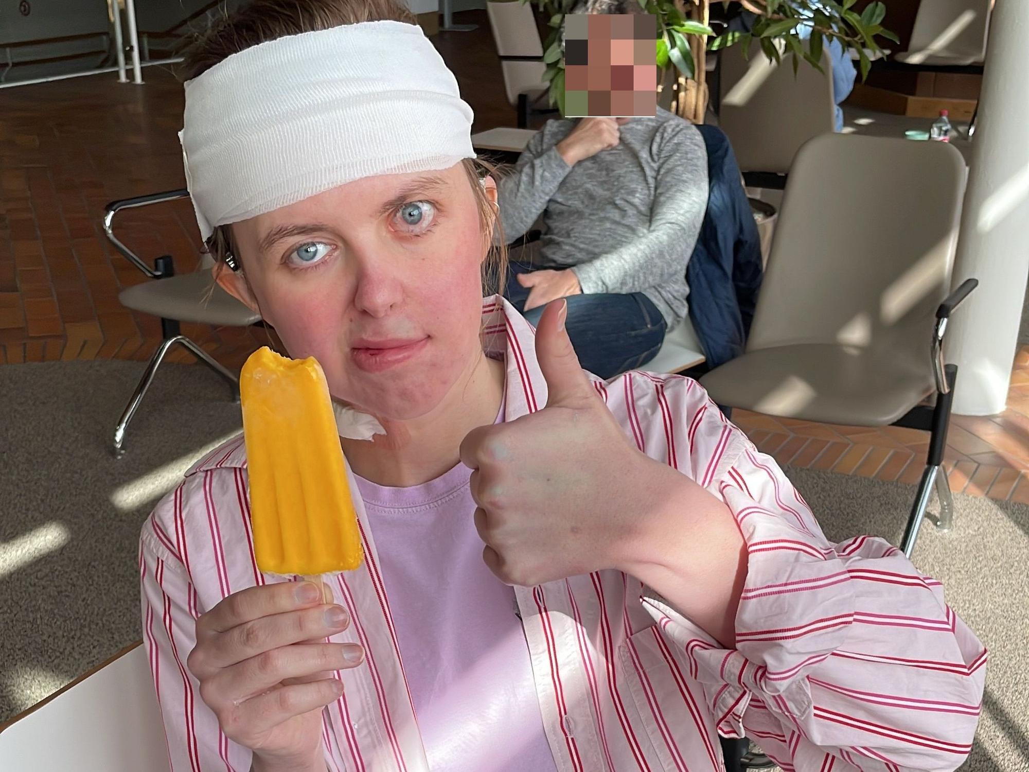 Greta hat einen Verband um den Kopf und hält einen Daumen hoch.