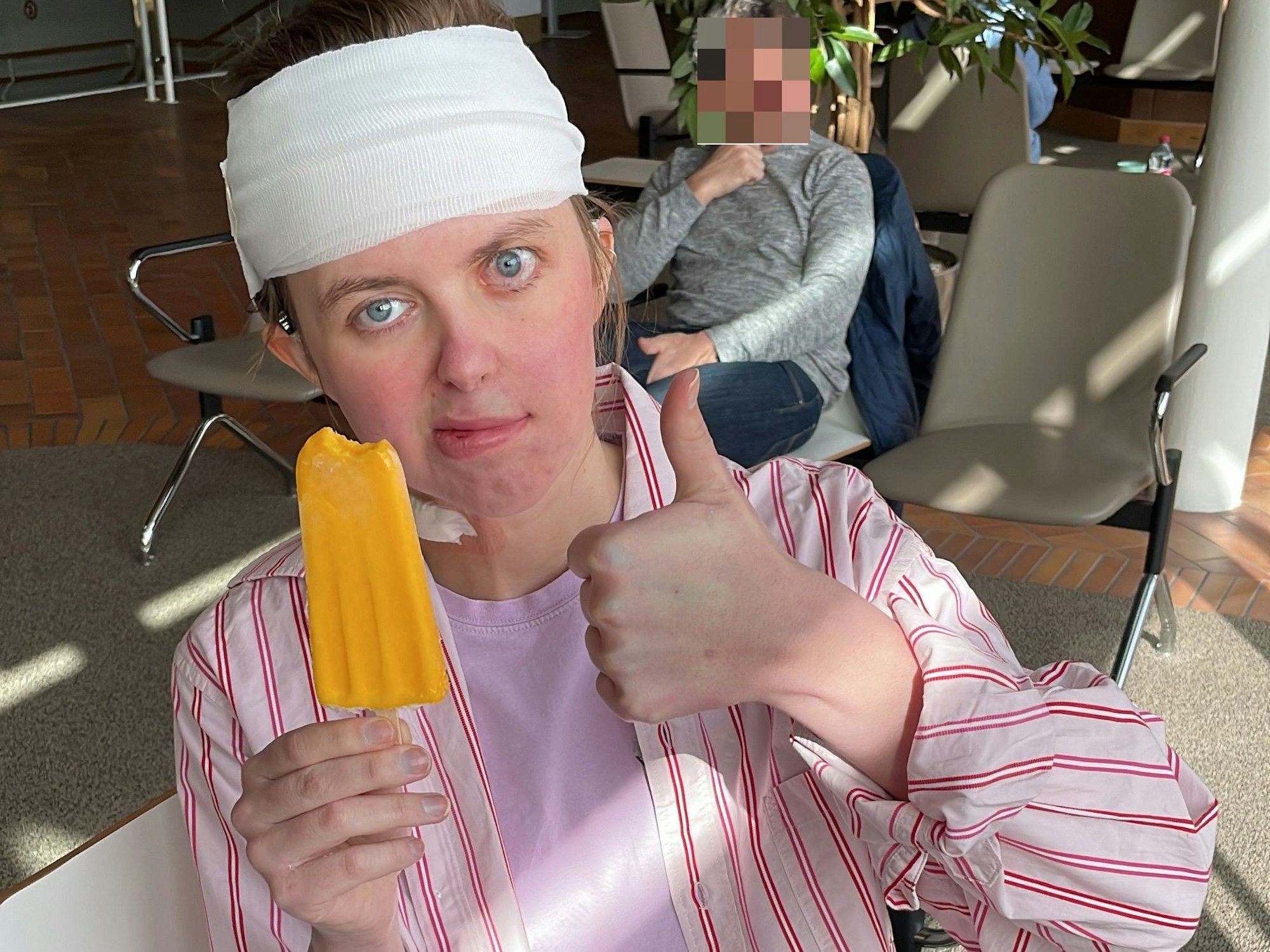 Greta hat einen Verband um den Kopf und hält einen Daumen hoch.