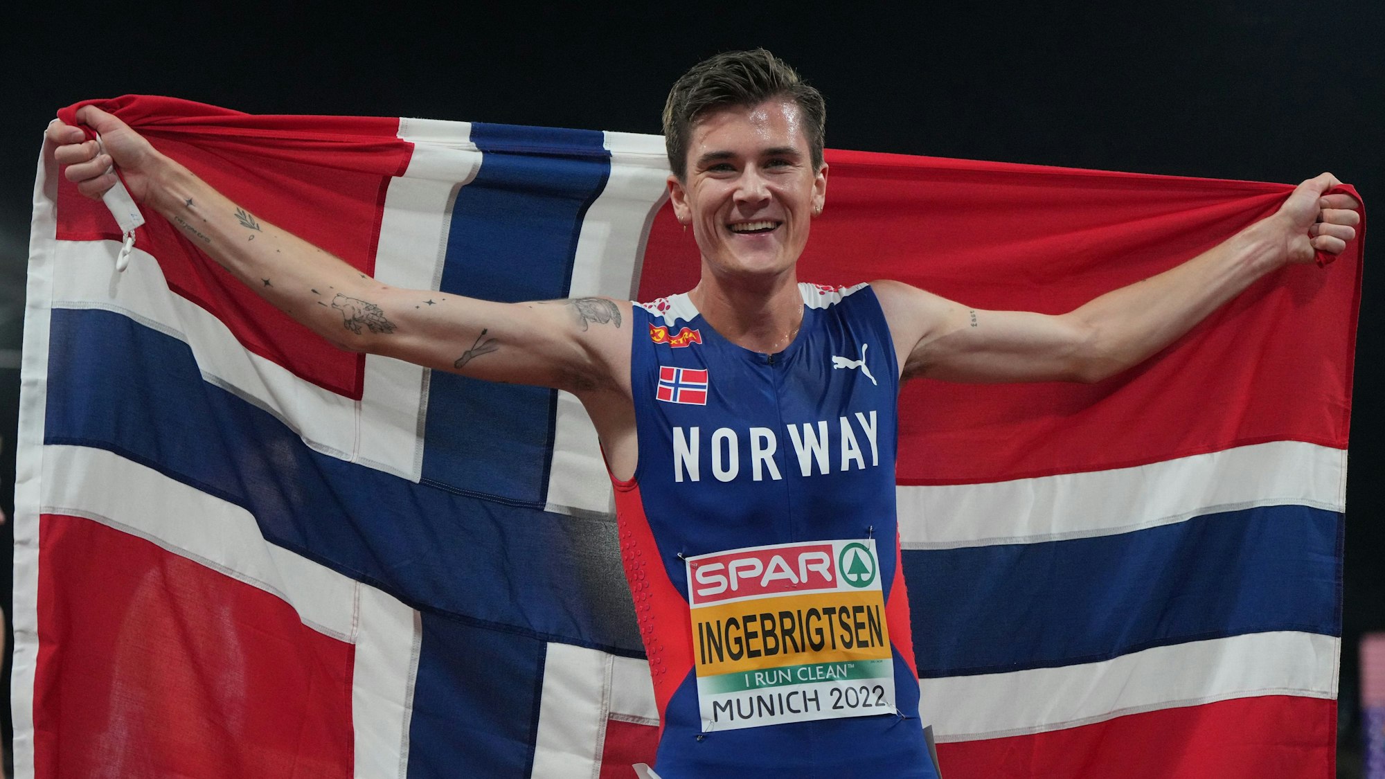 Jakob Ingebrigtsen jubelt mit Norwegen-Flagge.