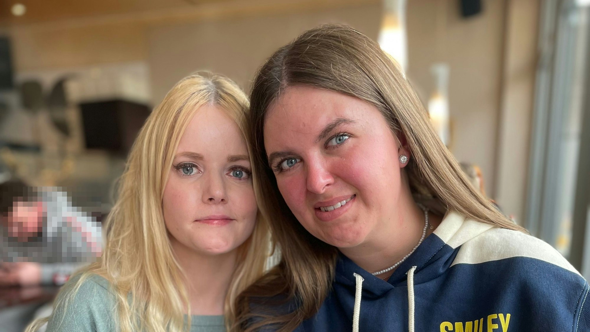 Zwei junge Frauen halten die Köpfe zusammen.