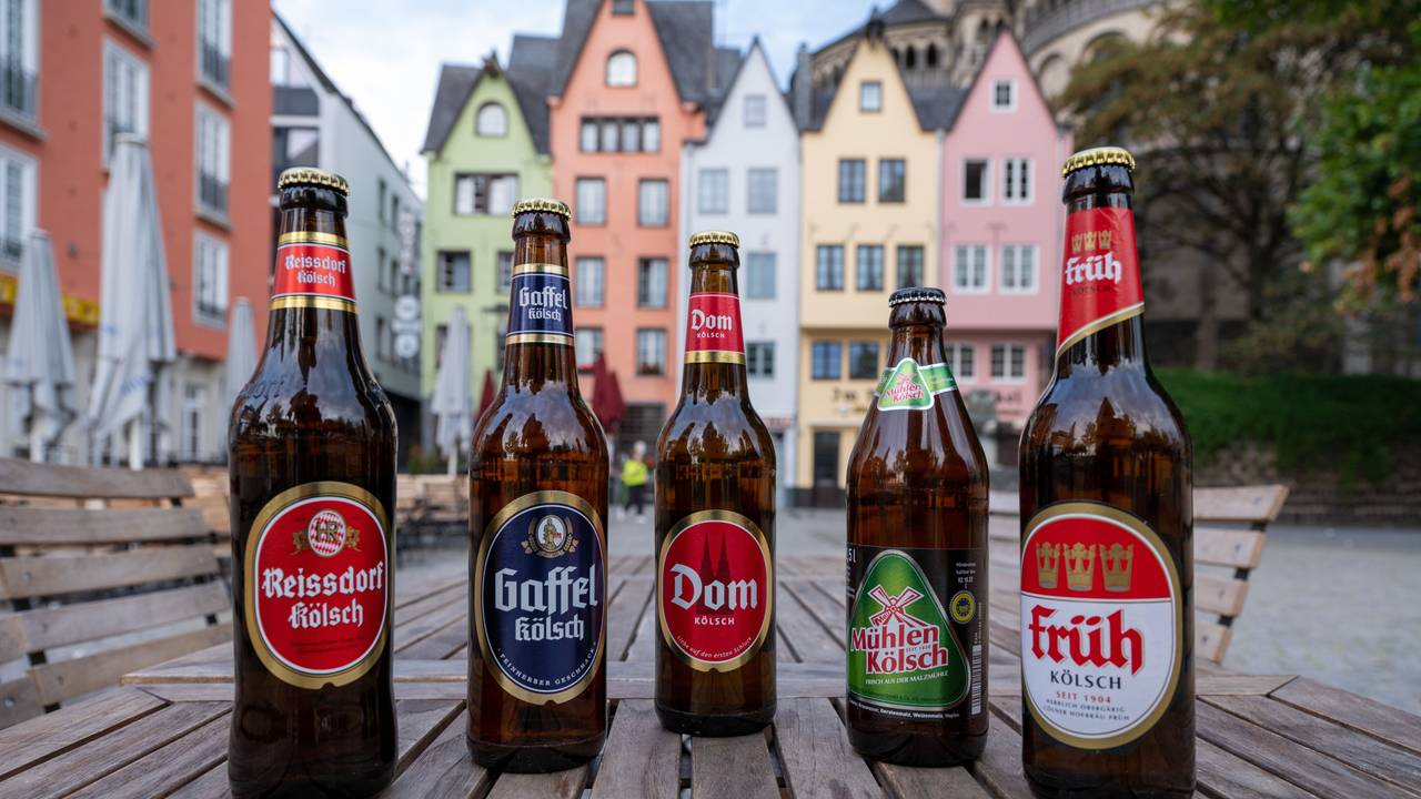 Fünf Bierflaschen von unterschiedlichen Marken stehen auf einem Tisch nebeneinander.