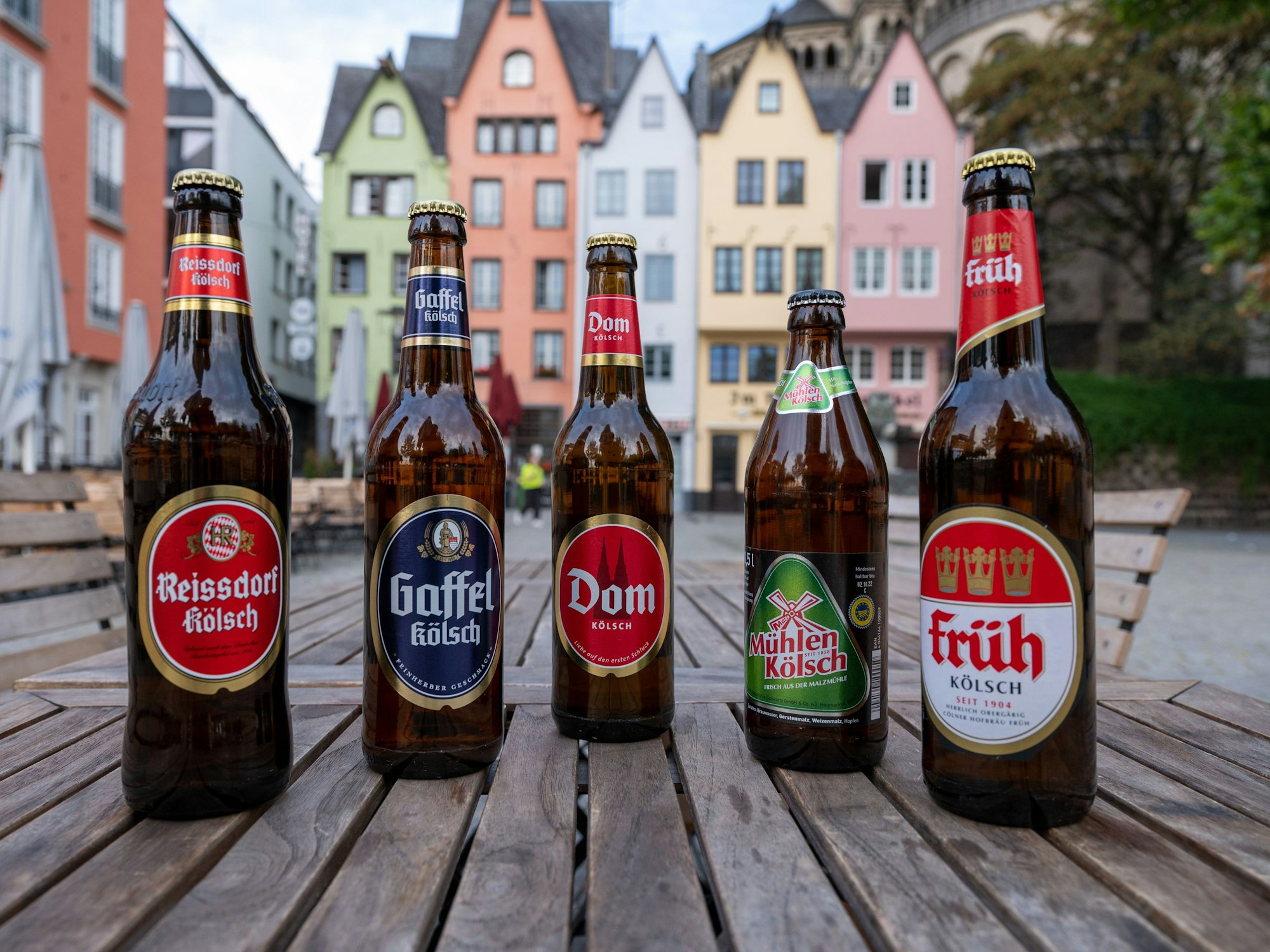 Fünf Bierflaschen von unterschiedlichen Marken stehen auf einem Tisch nebeneinander.