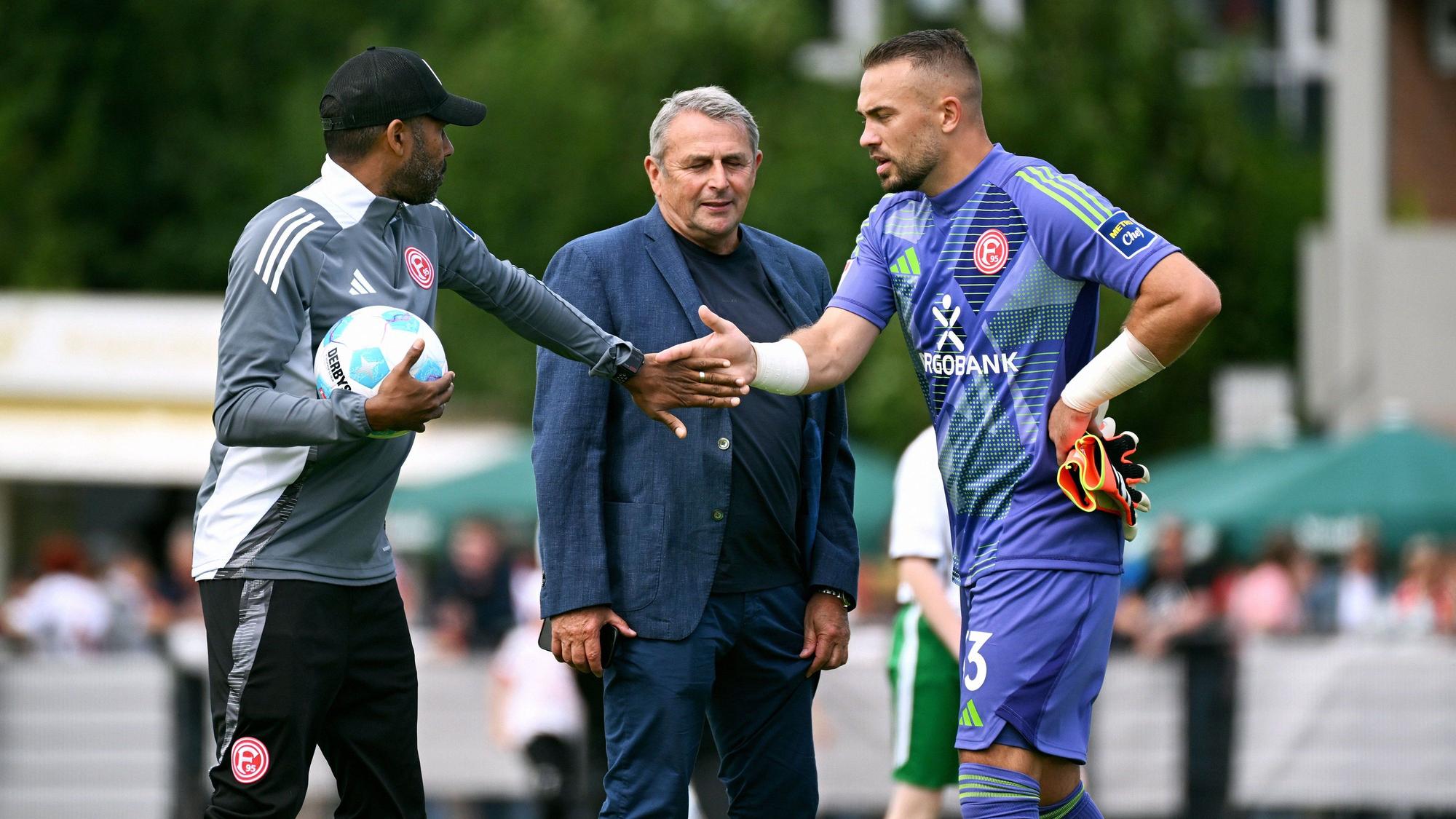 Daniel Thioune klatscht mit Florian Kastenmeier ab, Klaus Allofs lächelt.