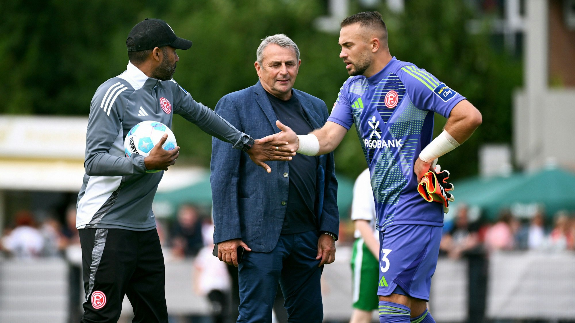 Daniel Thioune klatscht mit Florian Kastenmeier ab, Klaus Allofs lächelt.